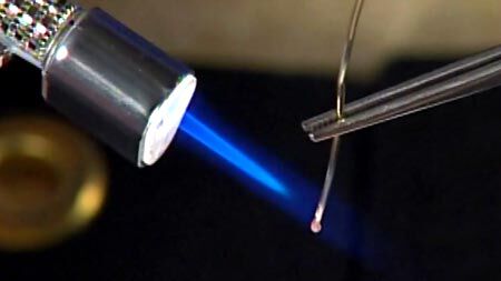 Enlarged image of a butane torch heating the end of silver wire.